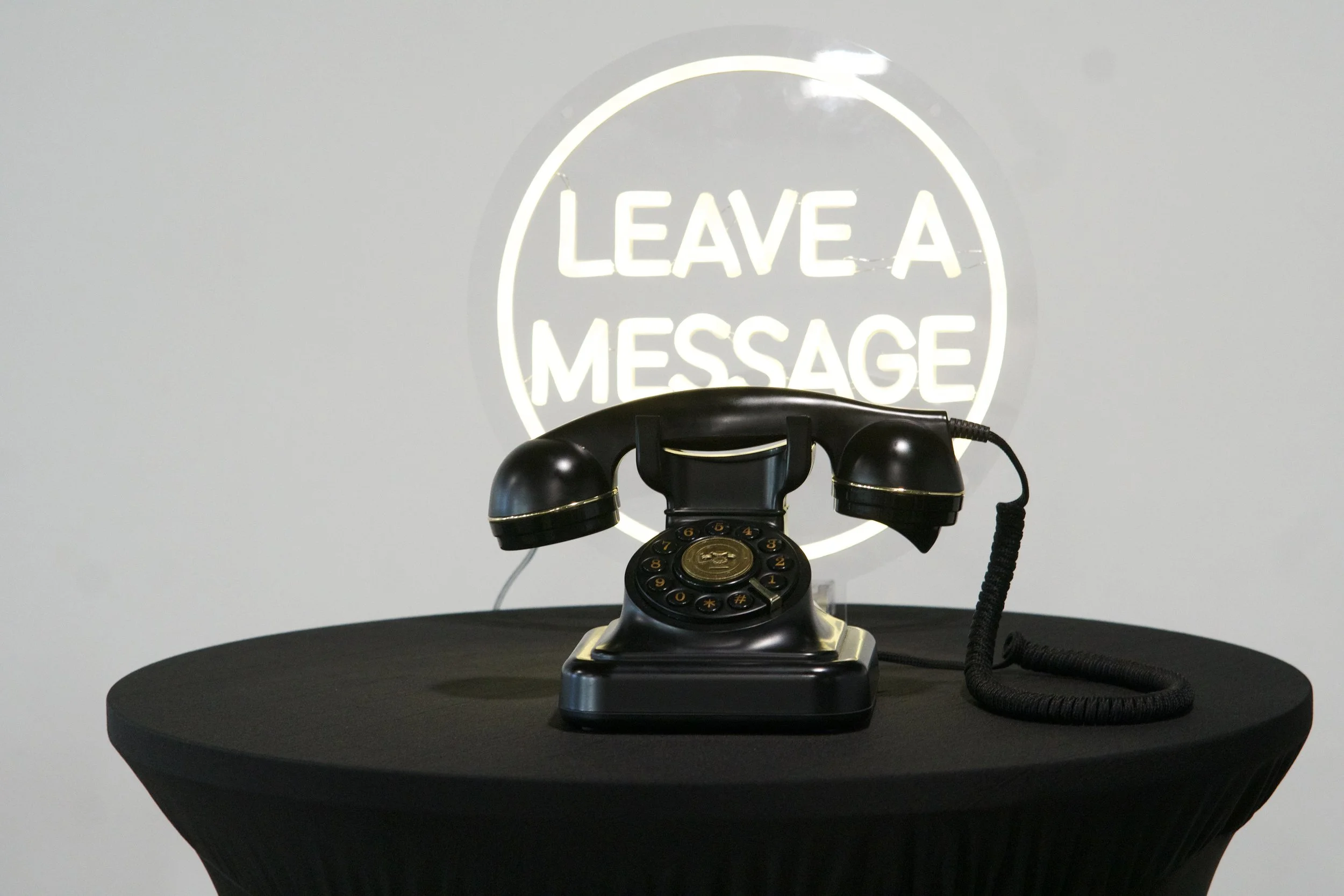 vintage black telephone beside a lit Leave a Message sign at a Gatsby reception