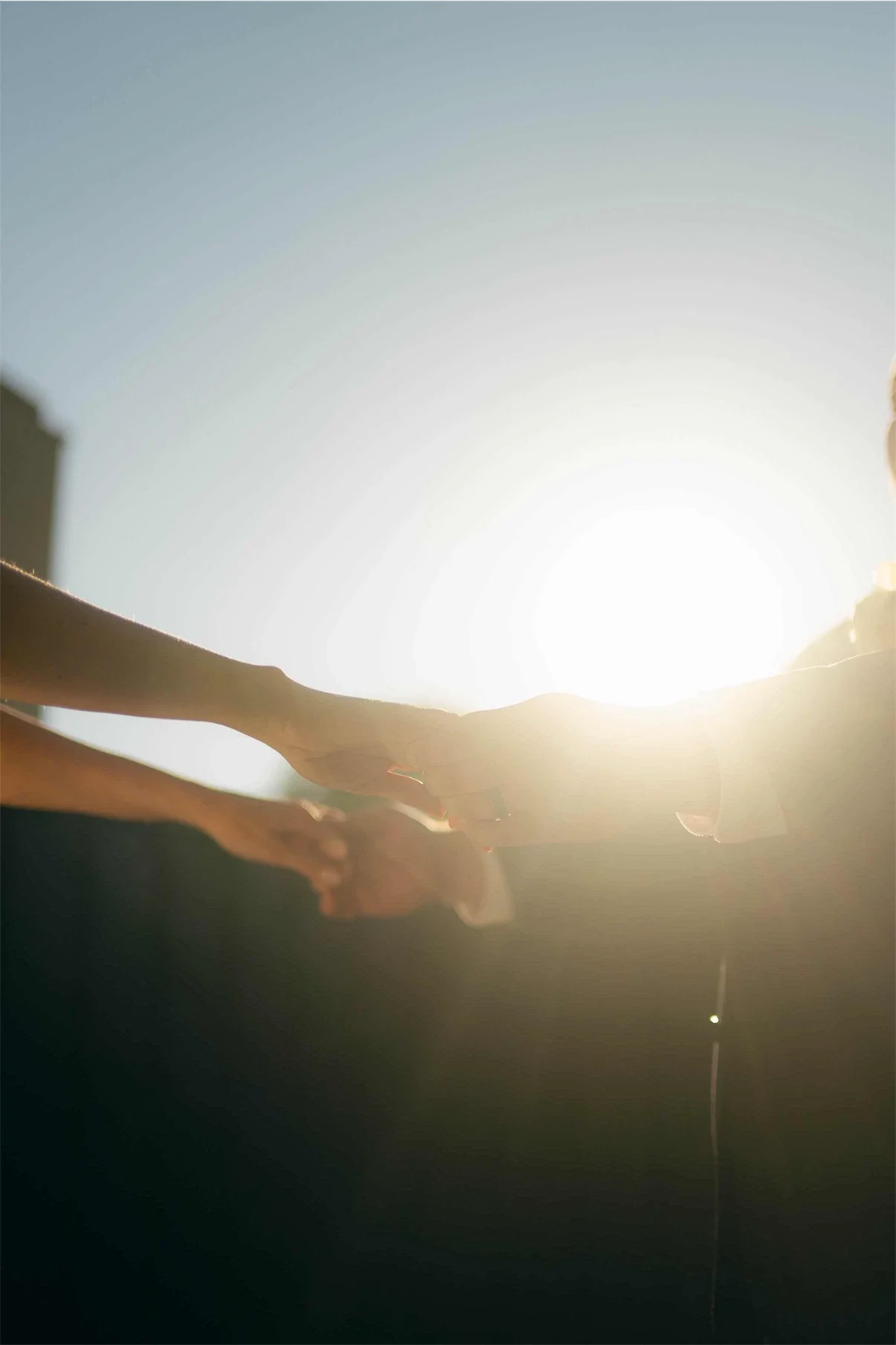 couple-holding-hands-backlit-golden-sun-flare.webp