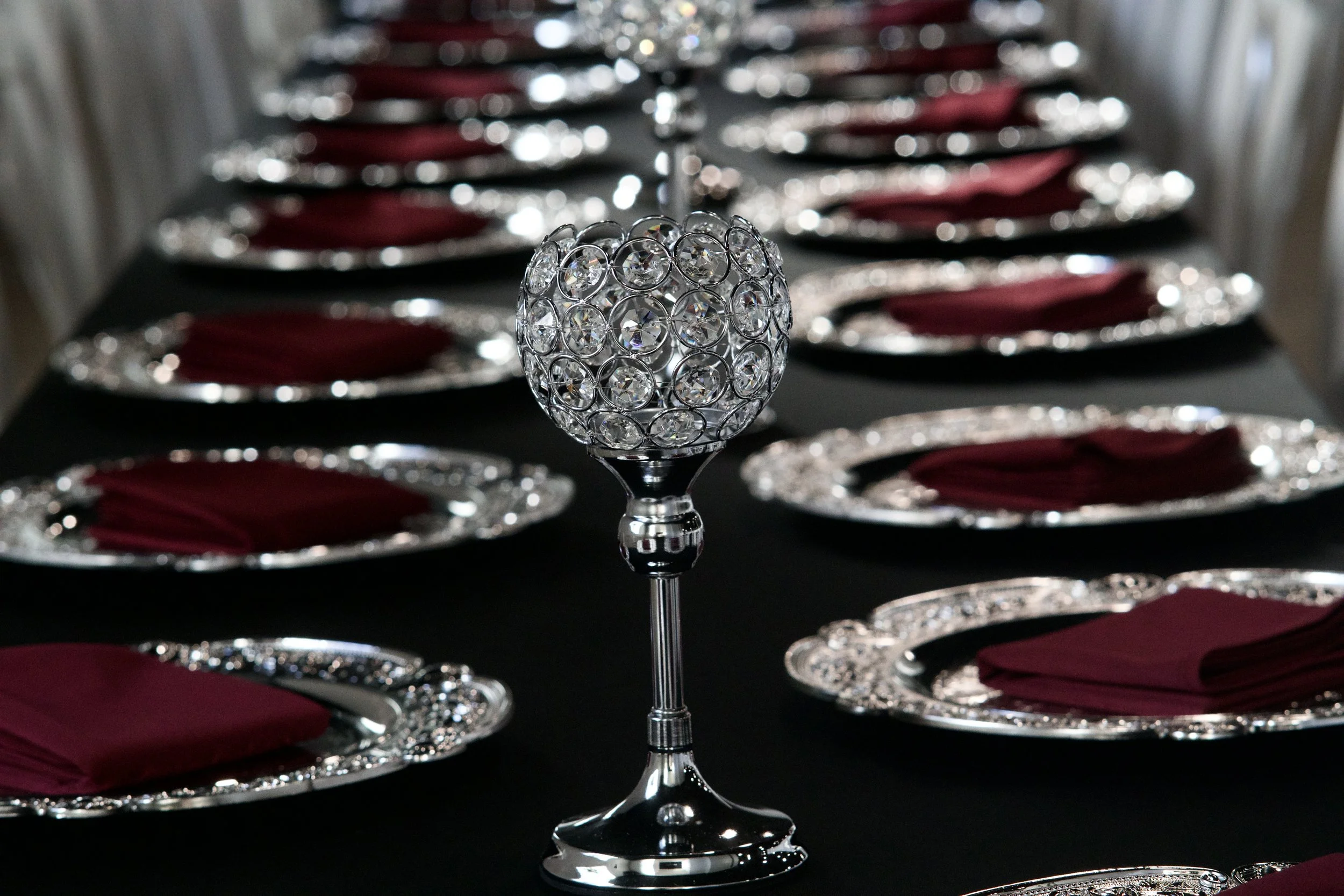 crystal goblet style candle holder centered on a black tablecloth reception table