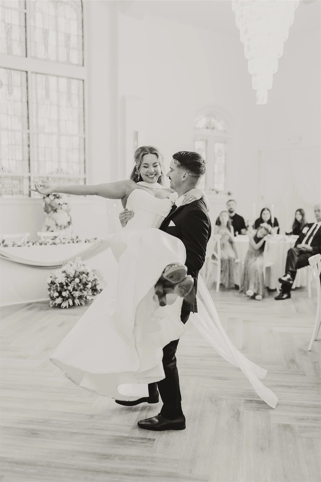 Groom dipping laughing bride during first dance at reception black and white