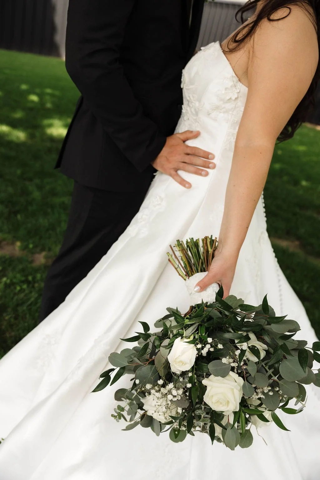 body-portrait-groom-touches-bride-waist-holding-bouquet-white-flowers.jpg