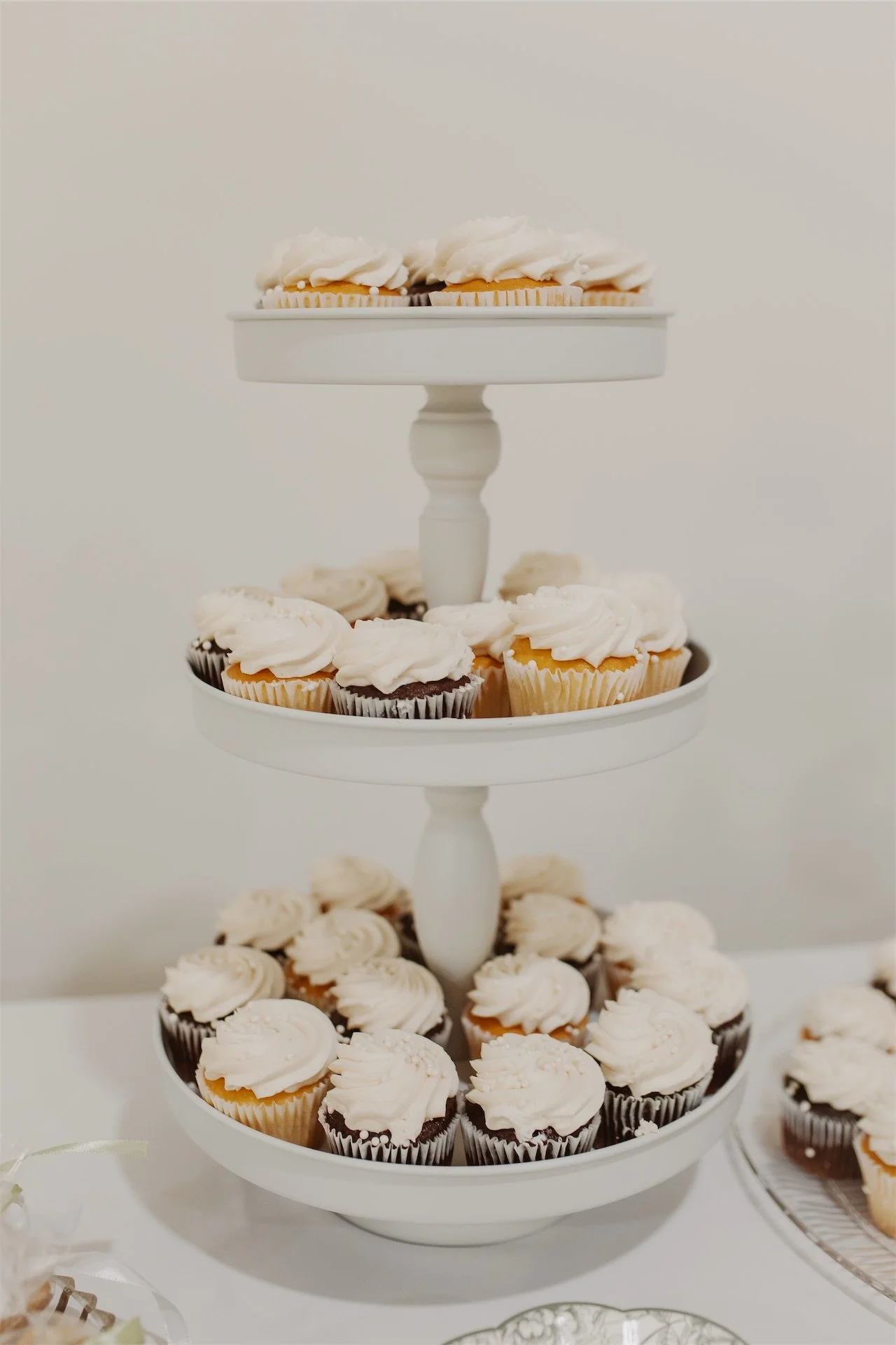 Three tier cupcake stand with frosted vanilla and chocolate wedding desserts
