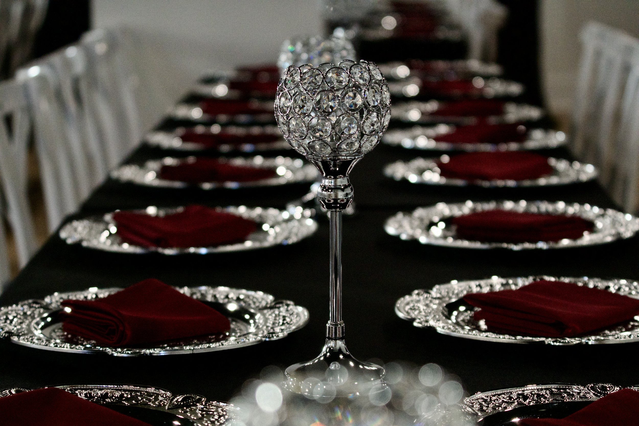 crystal goblet centerpiece rising above a row of burgundy napkin place settings