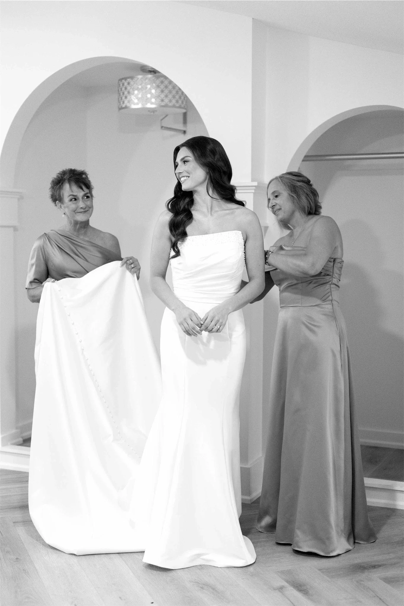 mothers-helping-bride-with-gown-train-black-and-white.webp