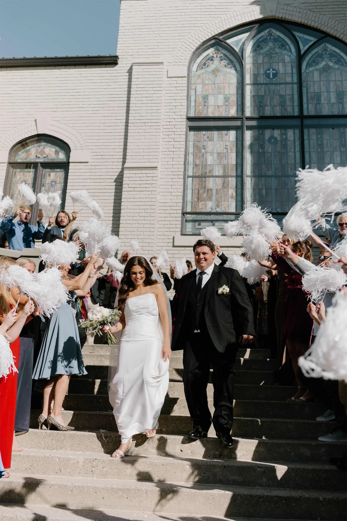 couple-exit-front-steps-white-pom-pom-send-off.webp