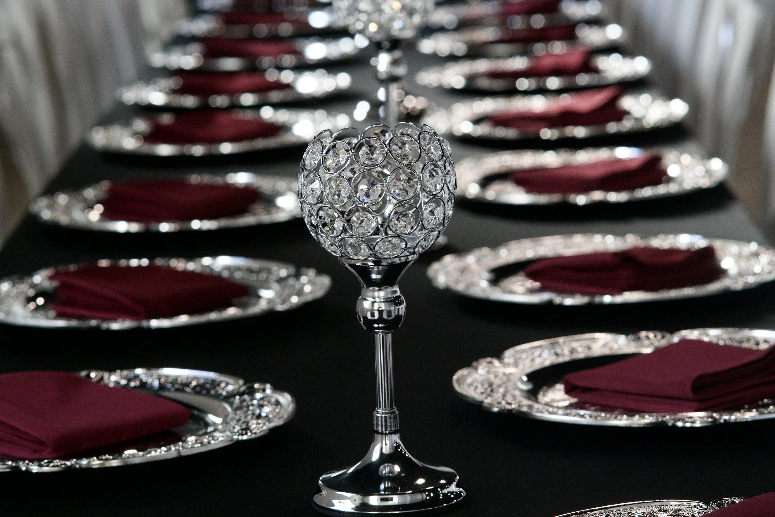 crystal ball candle holder standing among silver charger place settings