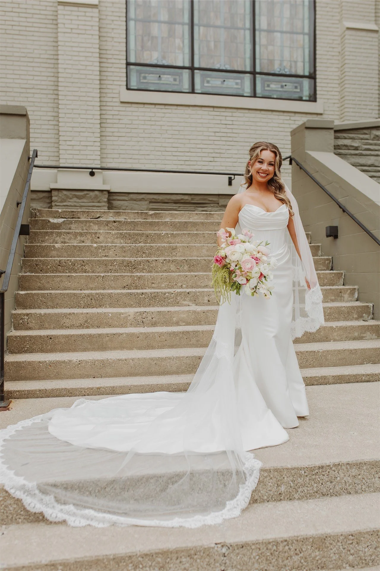 Bride in strapless gown walking down stone steps at historic church wedding venue