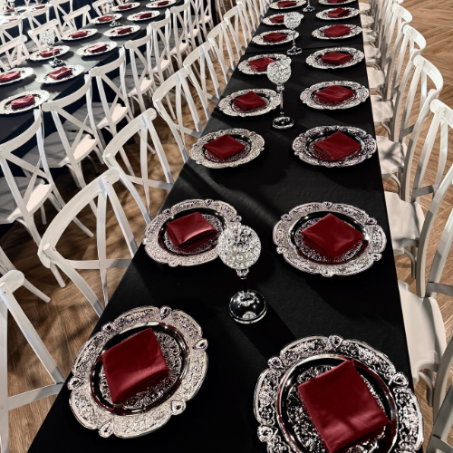 overhead angle of two black linen tables set with silver chargers and crystal centerpieces