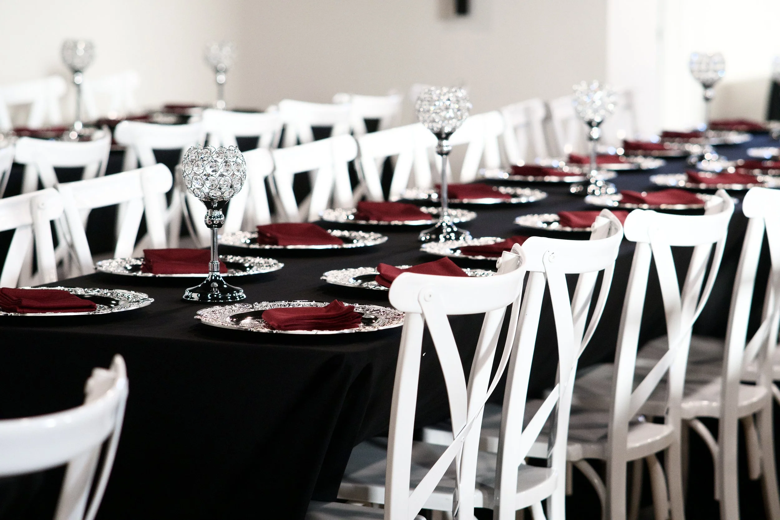 row of reception tables lined with crystal candle holders and burgundy napkins