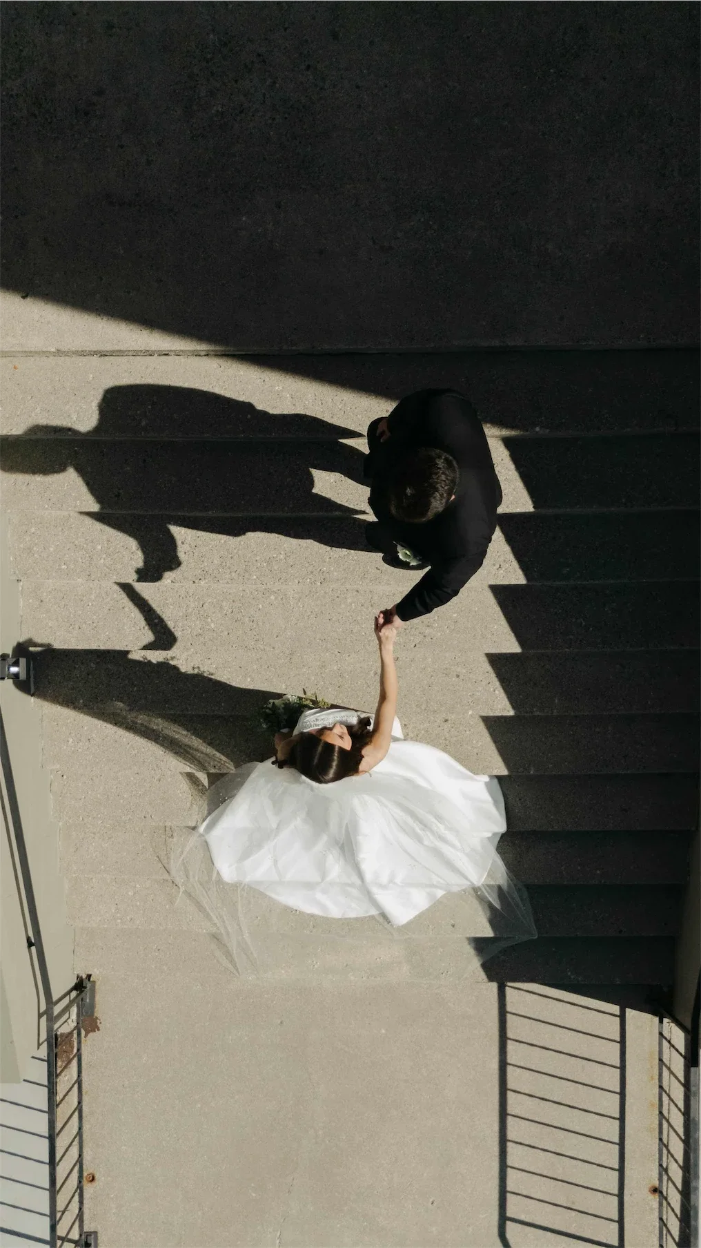groom-reaching-for-bride-chapel-steps-aerial-wedding-photo.webp