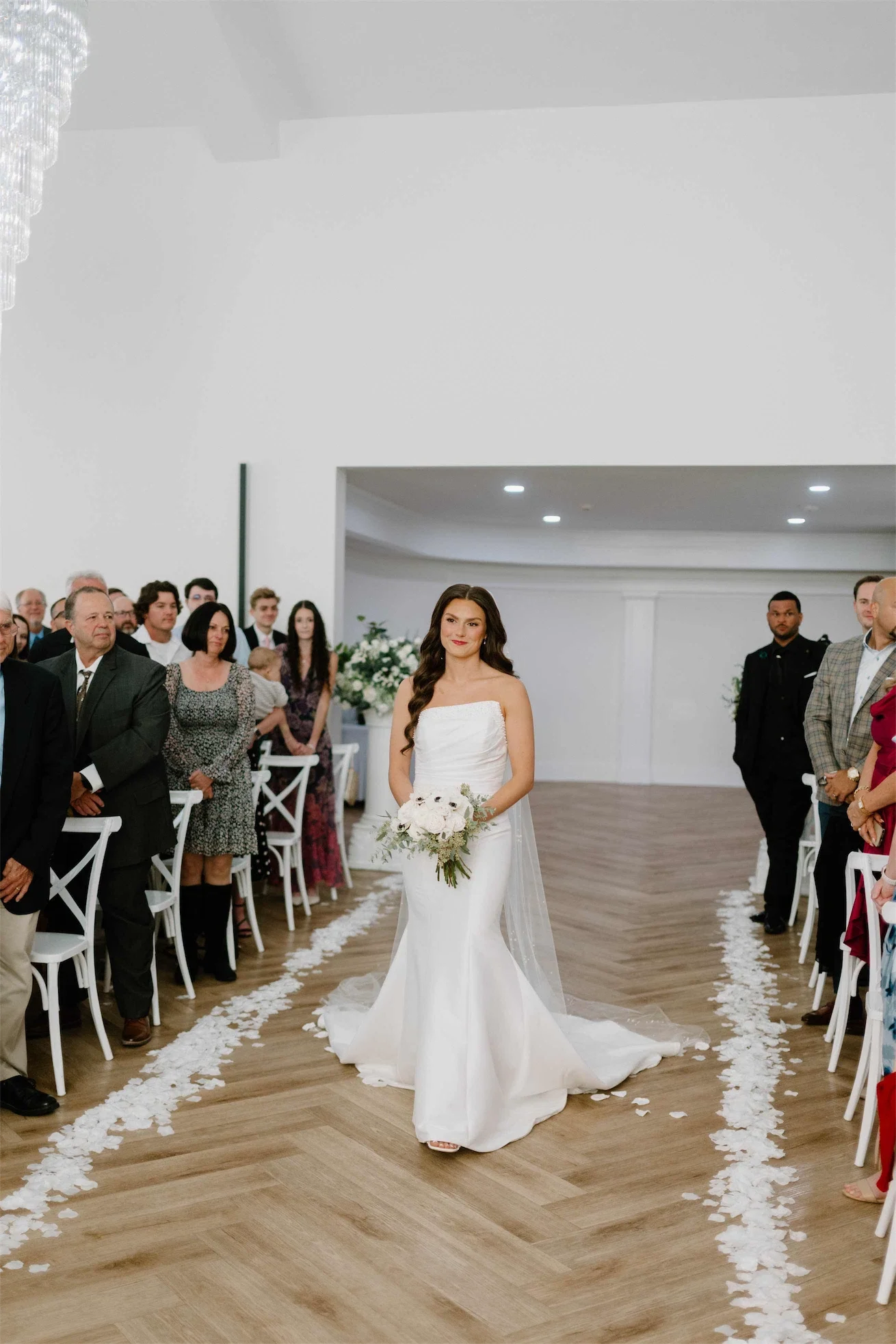 bride-walking-down-aisle-petal-lined-herringbone-floor.webp