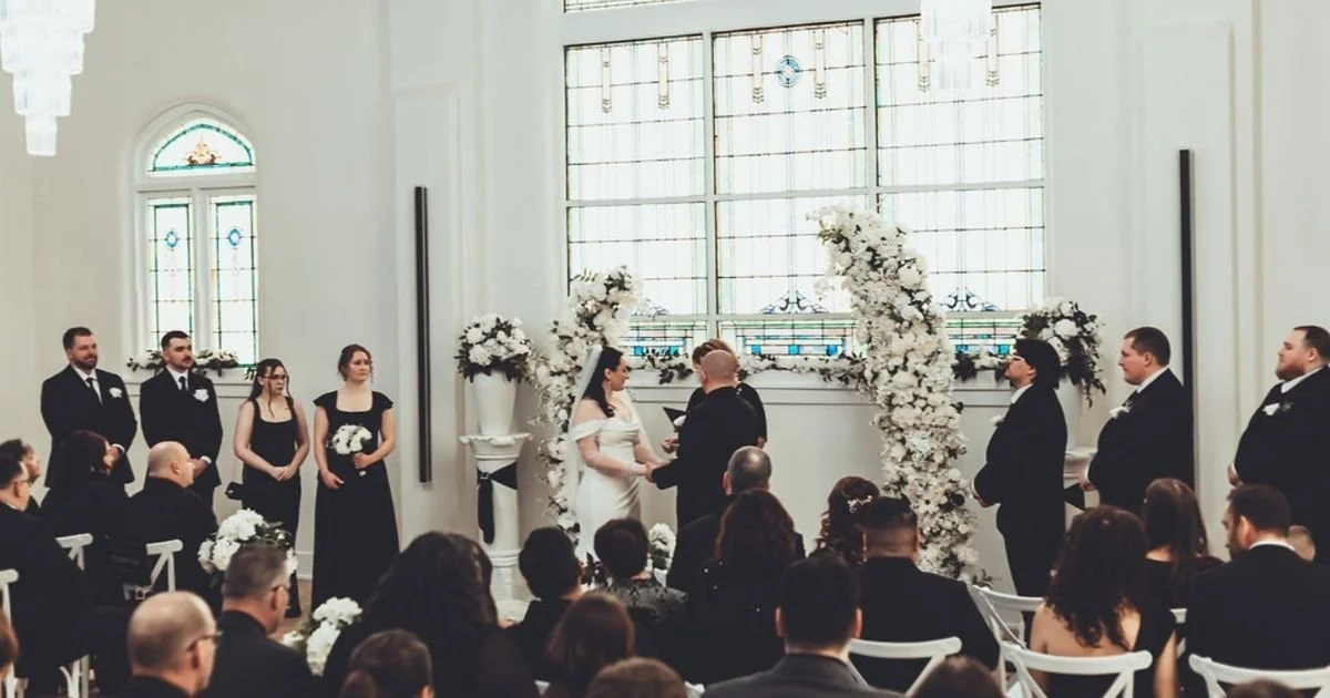 bride and groom exchanging vows beneath stained glass windows at a black tie Indiana wedding
