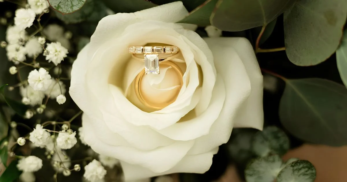 wedding ring nestled inside a white rose with gypsophila and eucalyptus greenery