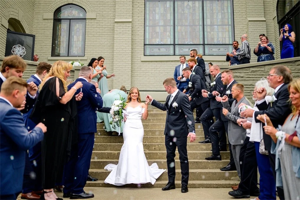 Guests line the church steps to cheer for the newlyweds as they walk through the crowd