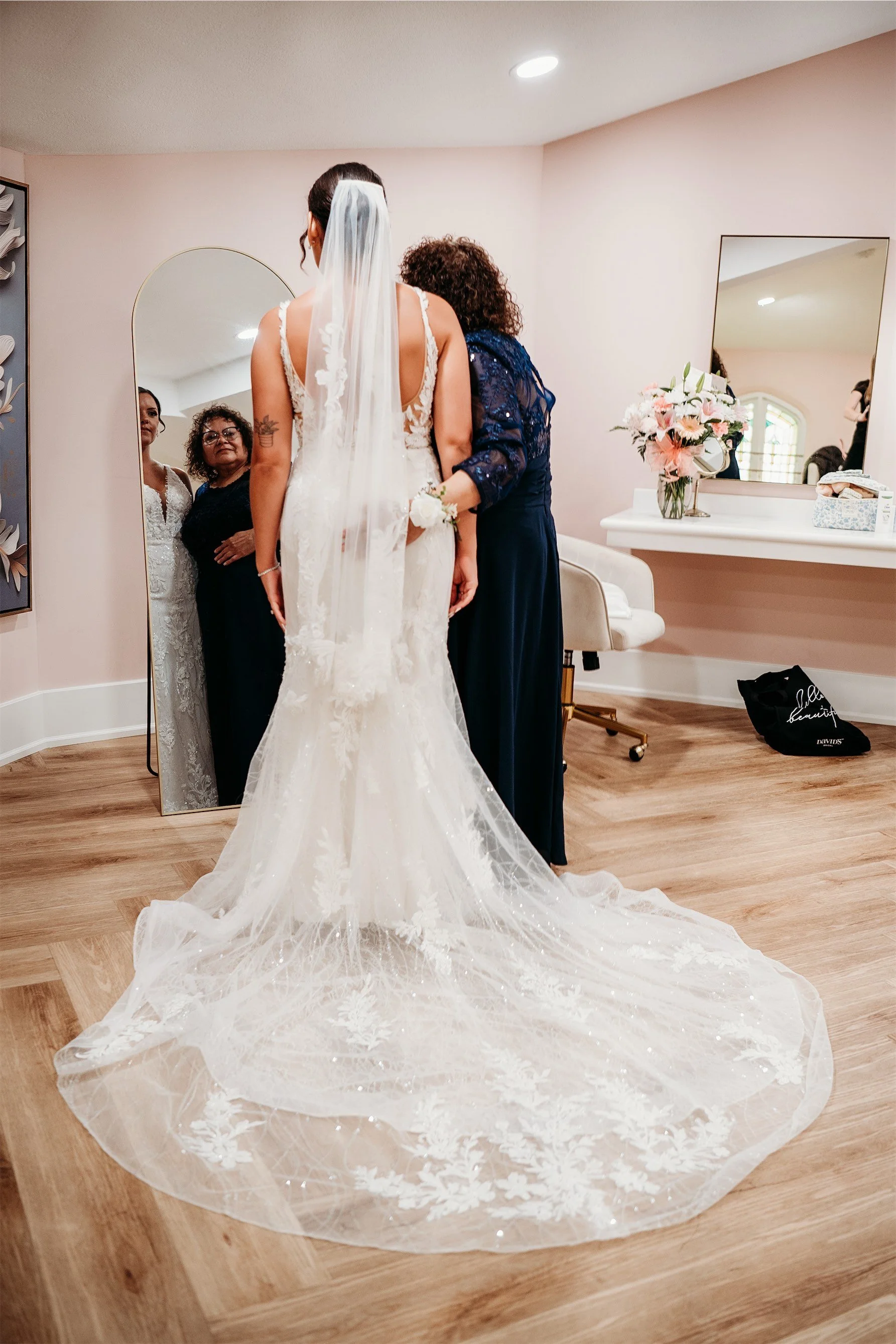 Bride in a lace gown with a long sparkling veil train in the blush pink bridal suite