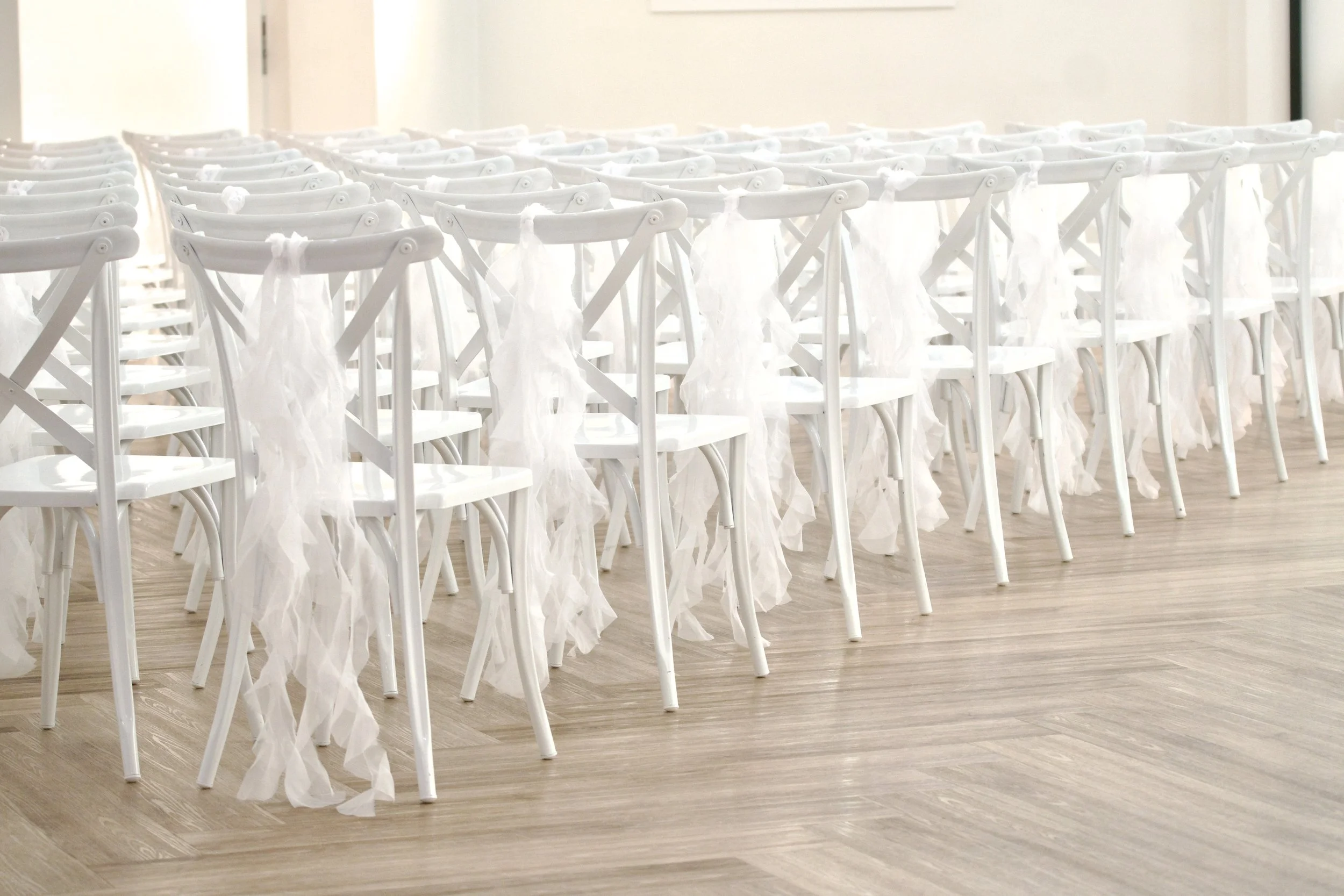 wedding ceremony aisle lined with draped white chairs on herringbone hardwood floors