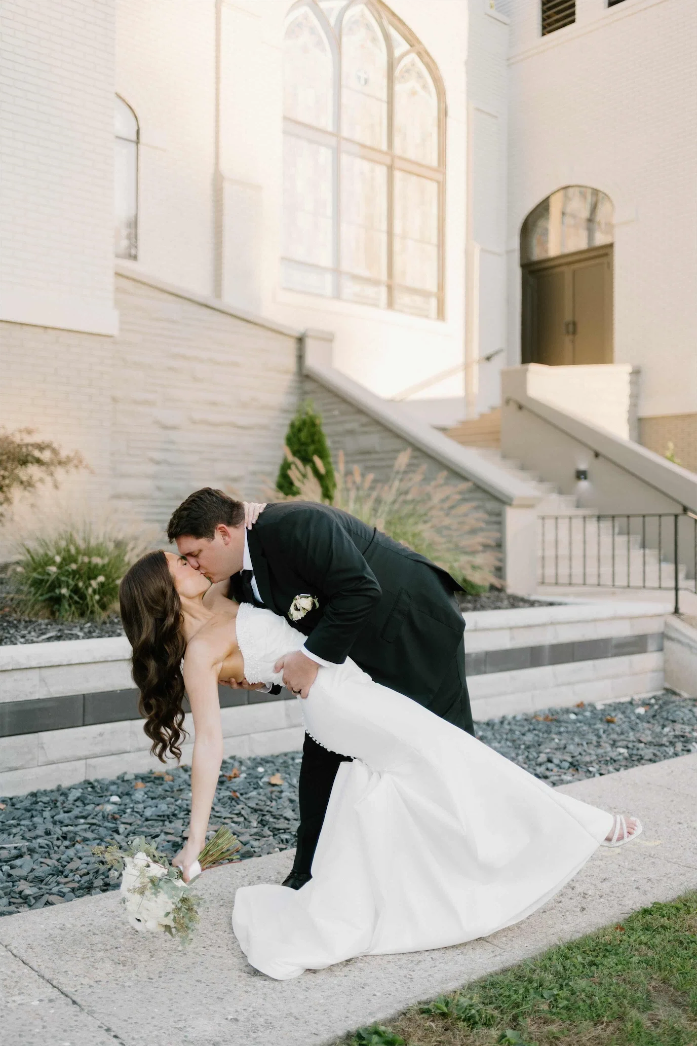 groom-dipping-bride-kiss-chapel-exterior.webp