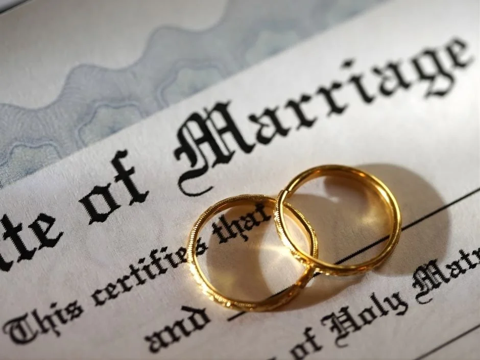 Two gold wedding bands resting on a marriage certificate for an Indiana newlywed couple