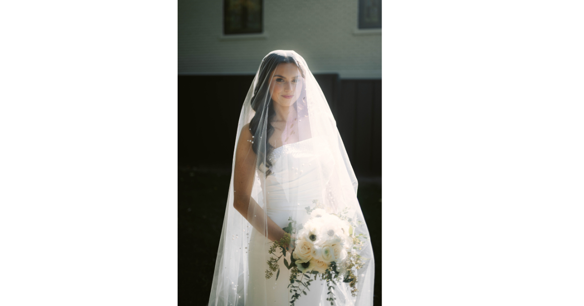 Bride in cathedral veil holding white bouquet poses inside historic church at Kaleidoscope Weddings