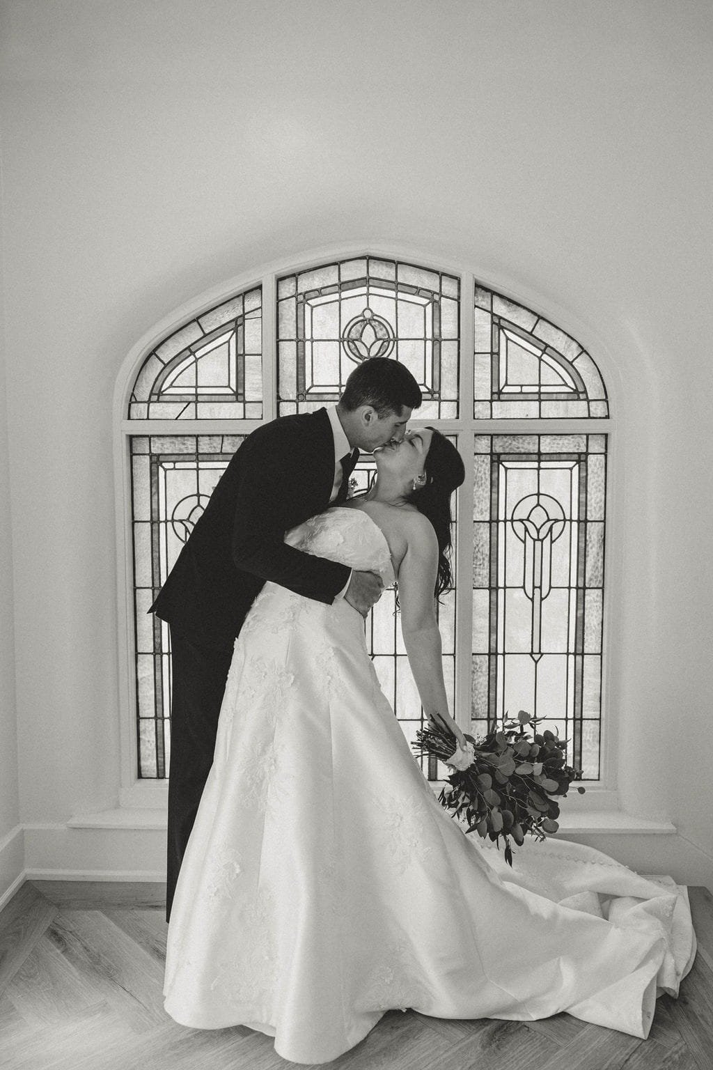groom-holds-bride-during-kiss-stained-glass-window-black-and-white.jpg