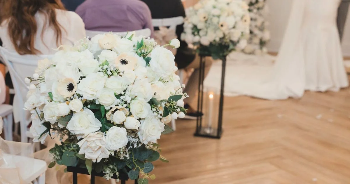 ivory and white floral arrangements lining a classic wedding ceremony aisle