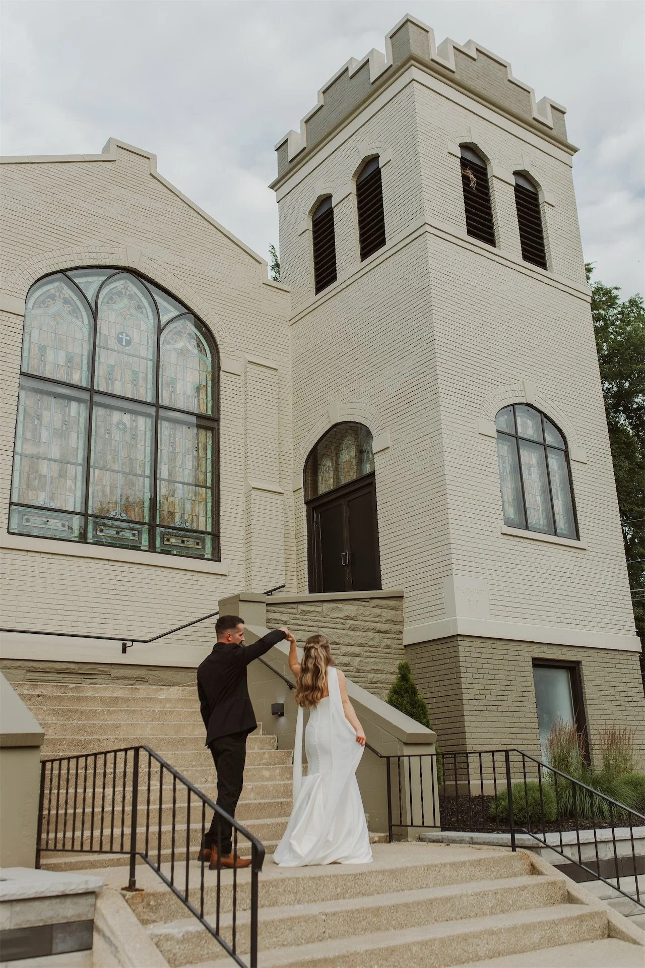 Bride and groom walking hand in hand up stone steps at church wedding venue