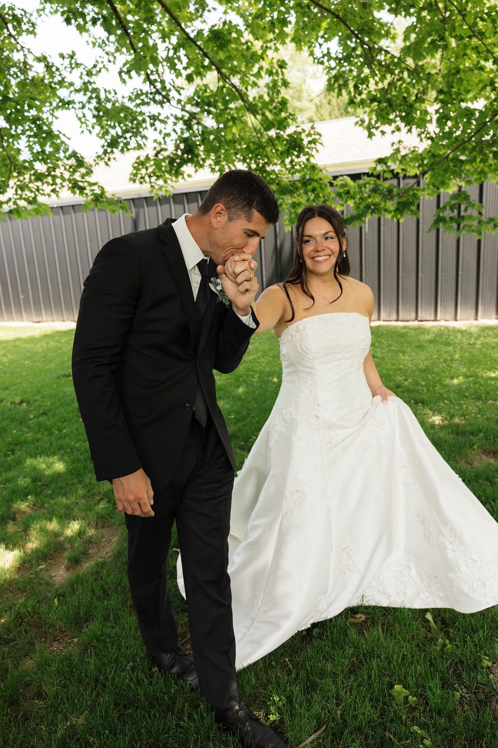 groom-kissing-brides-hand-wedding-outside.jpg