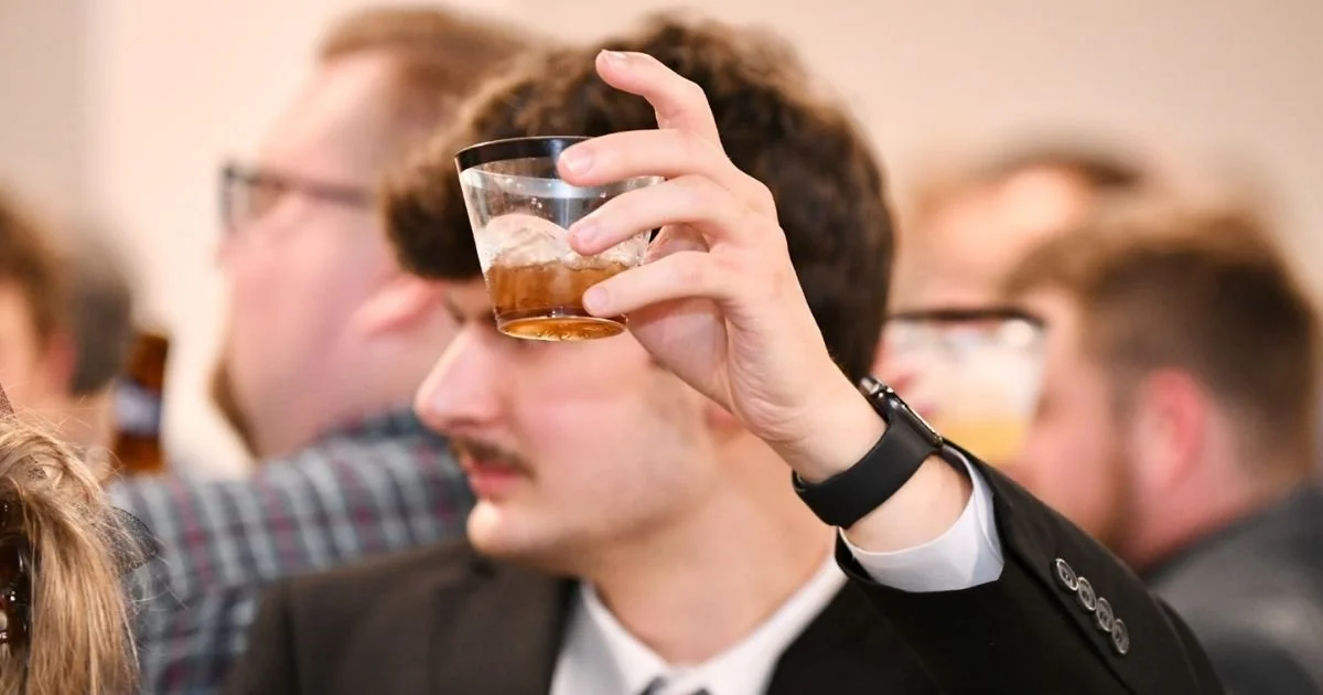 wedding guest raising a drink during a toast at the reception bar