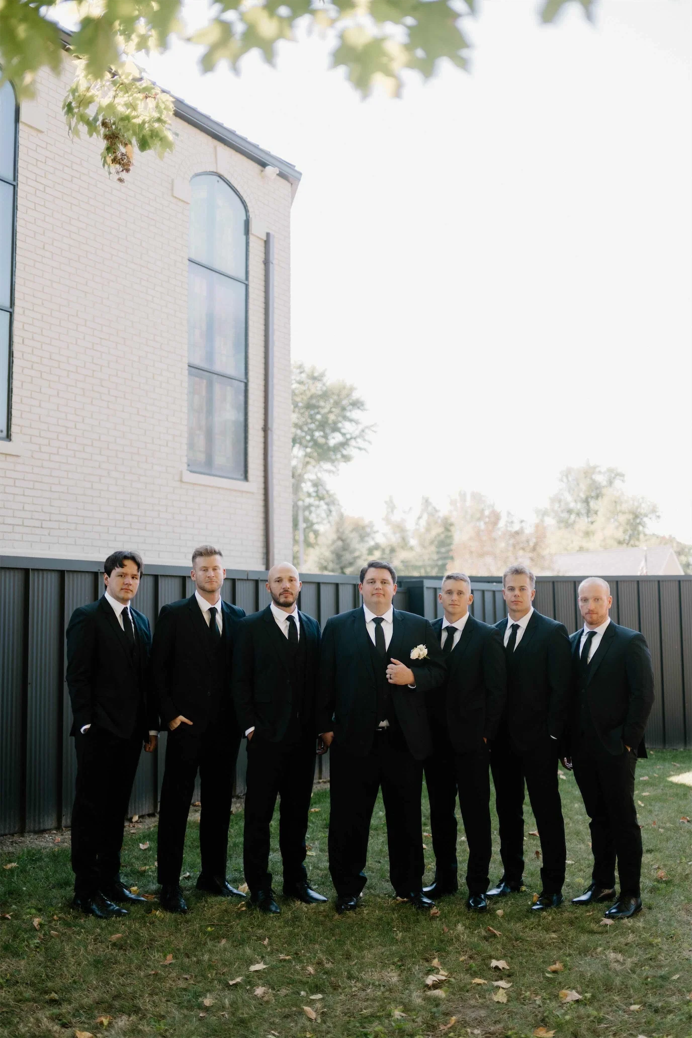 groom-and-groomsmen-black-suits-brick-chapel.webp