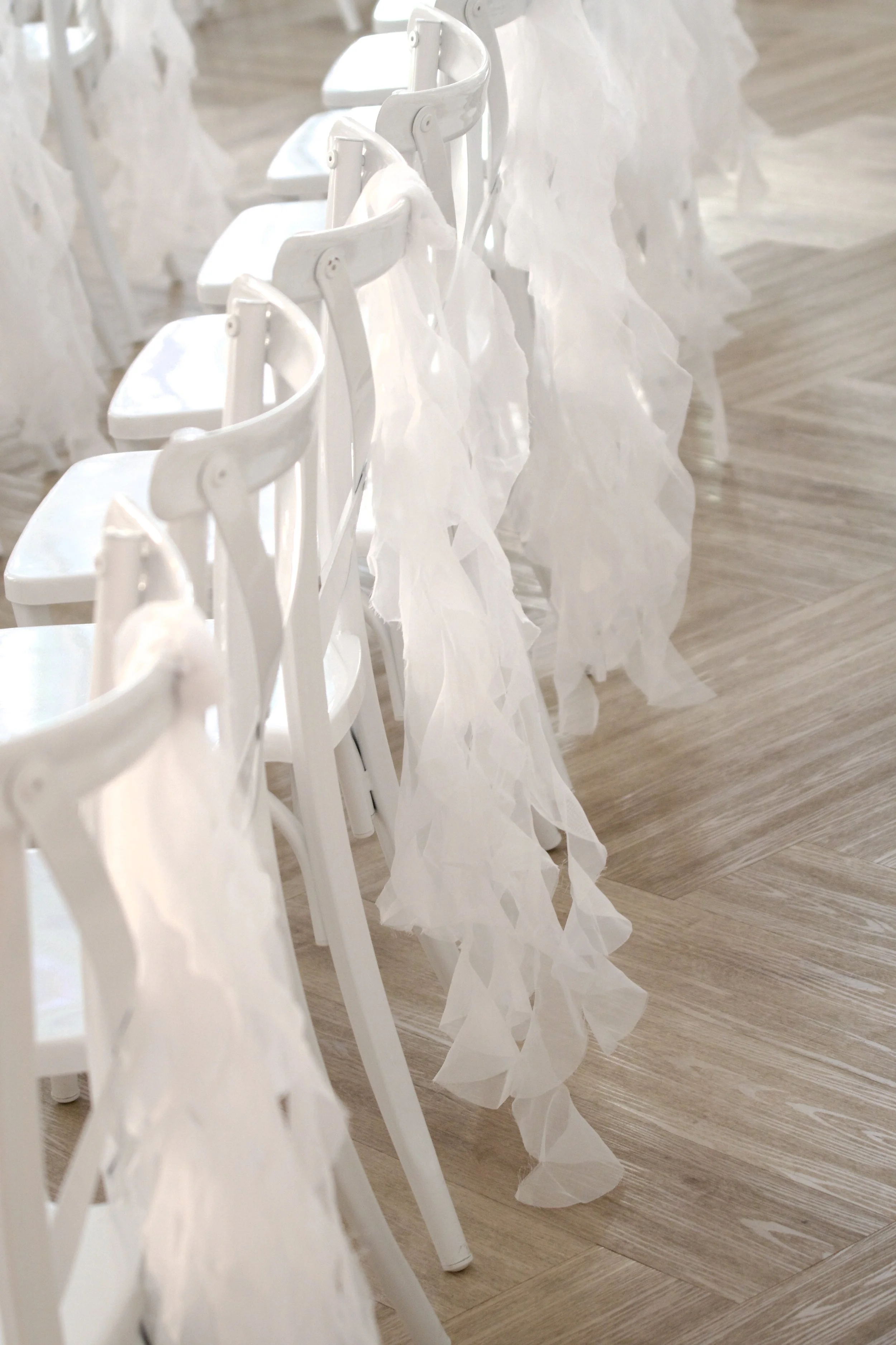close detail of frayed sheer chiffon sashes draped over ceremony chair backs