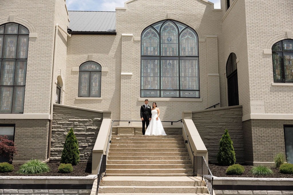 wide-view-newlyweds-church-steps-stained-glass.jpg