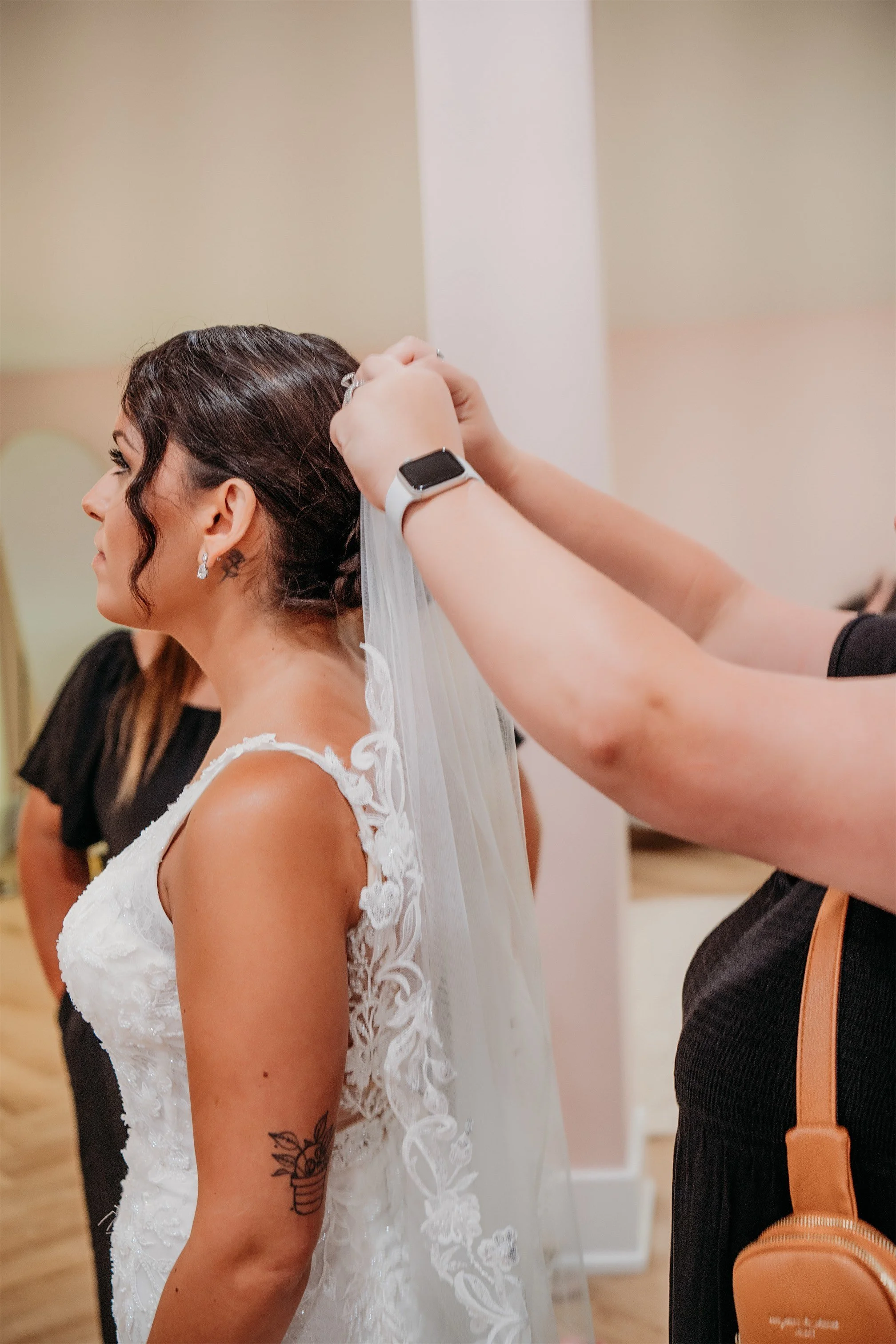 Bride having her lace veil pinned into her hair while getting ready in the bridal suite