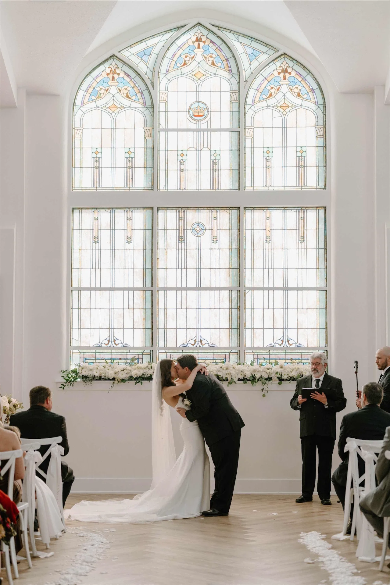 first-kiss-ceremony-under-stained-glass-window-indiana-chapel-wedding.webp