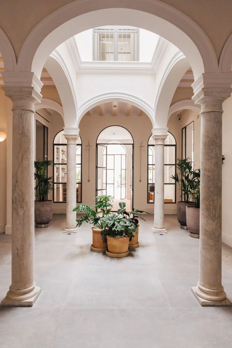 Hotel lobby with archway that brings in light and potted plants