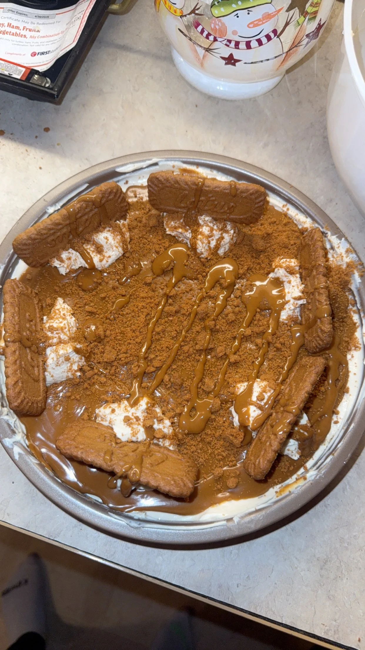 A dessert with whipped cream, graham crackers, crushed cookies, caramel drizzle, and crumbled cookies on top.