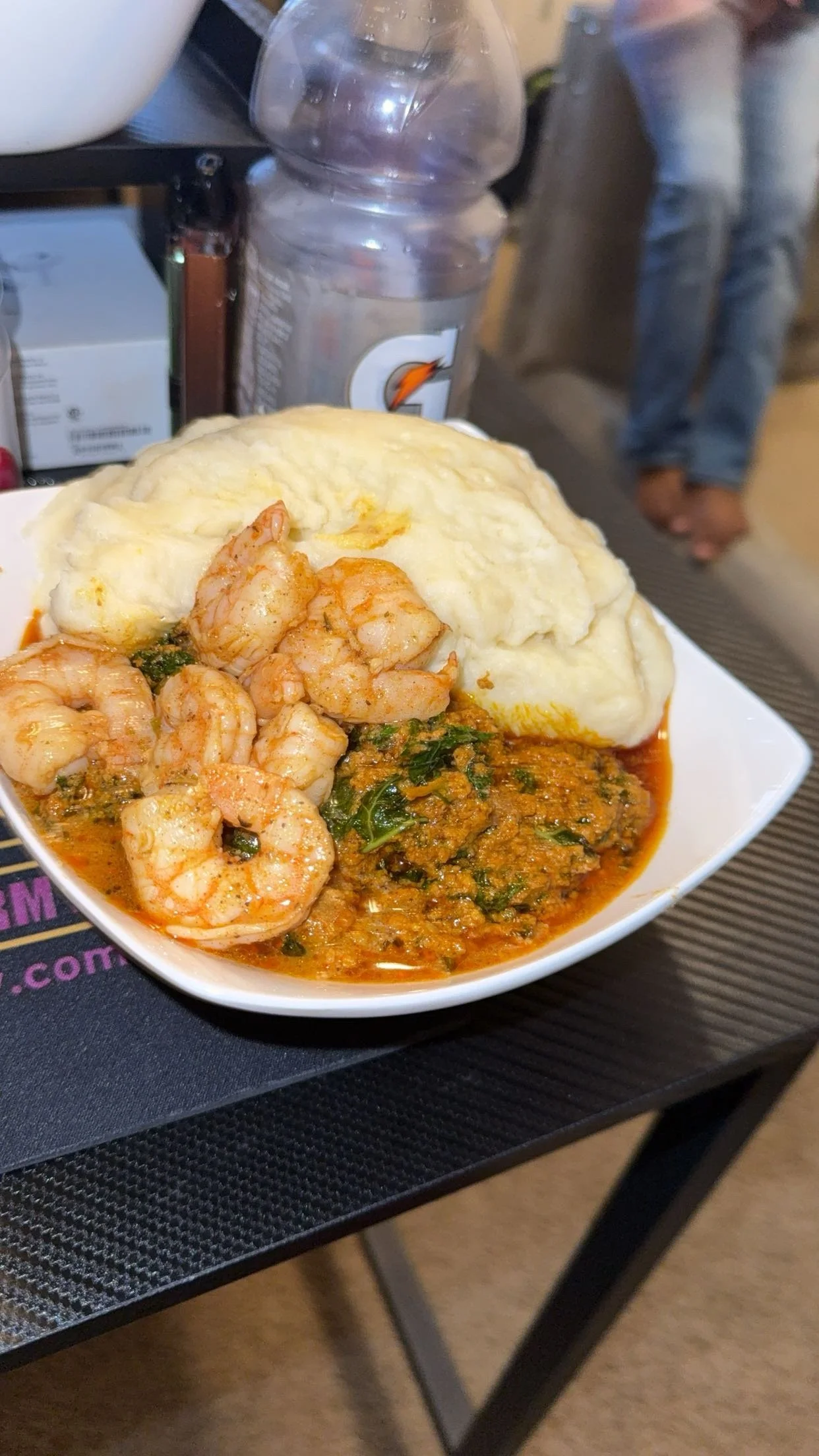 A bowl with shrimp, mashed potatoes, and a vegetable stew or curry.