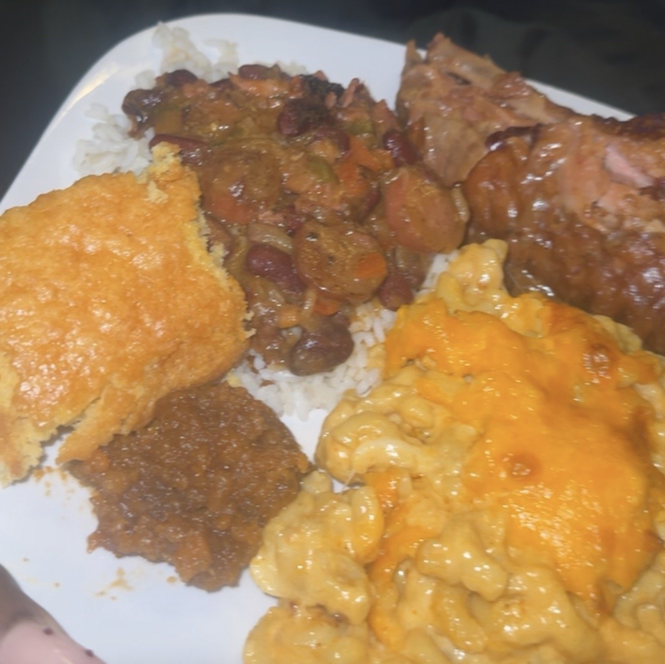 Plate of rice with fried chicken, chili, macaroni and cheese, beans, and meatloaf.