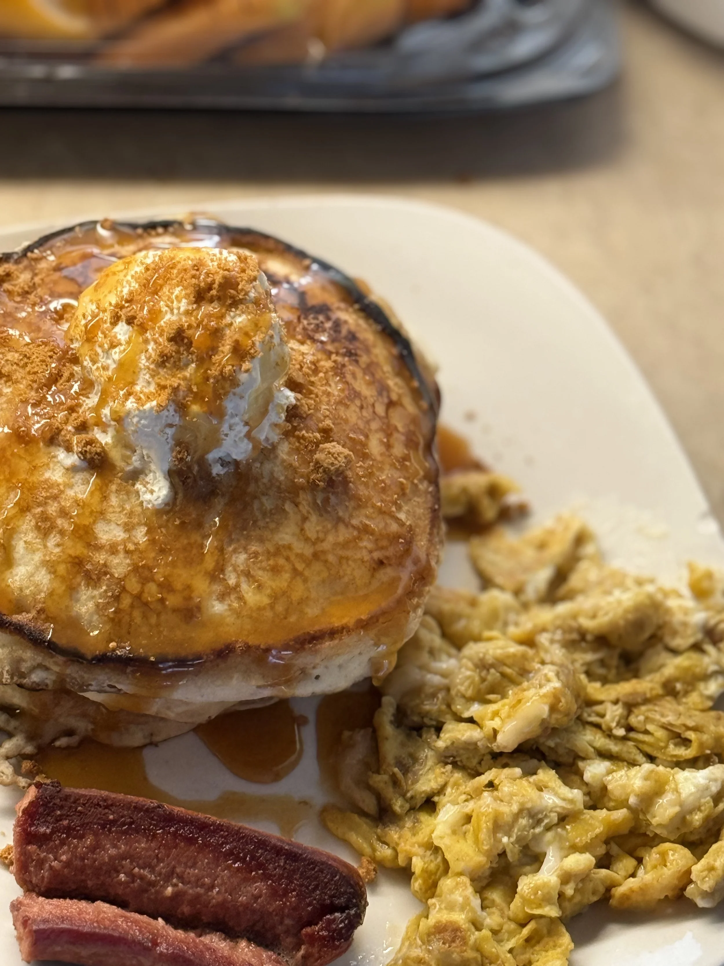 Breakfast plate with a fried egg topped with cheese and gravy, scrambled eggs, bacon, and a biscuit.