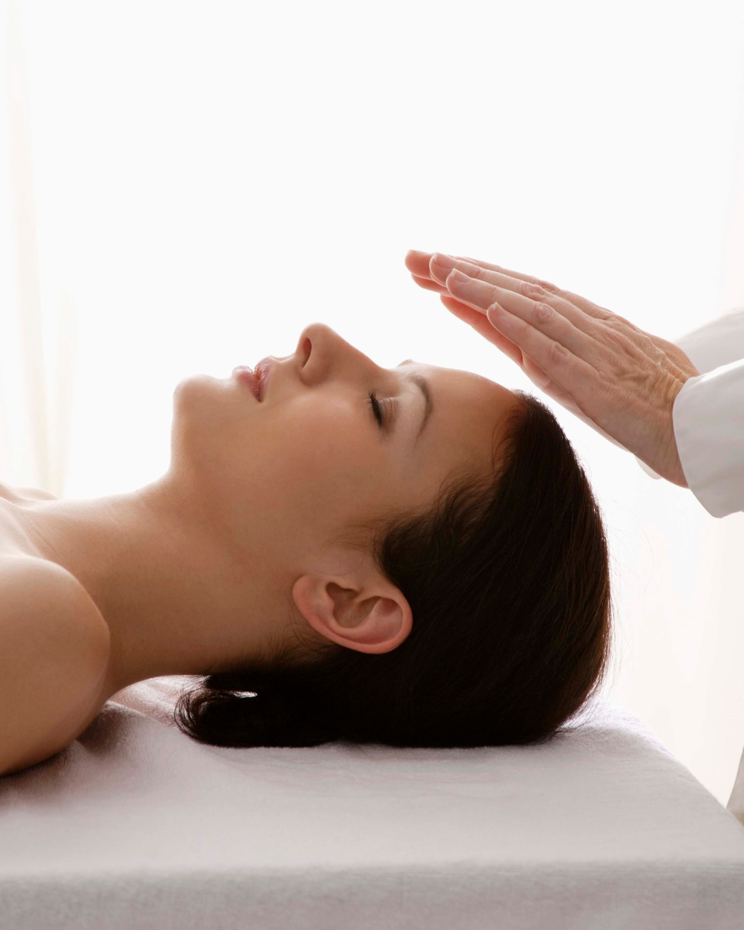 A woman receiving a facial treatment from a professional in a bright, clinical setting.