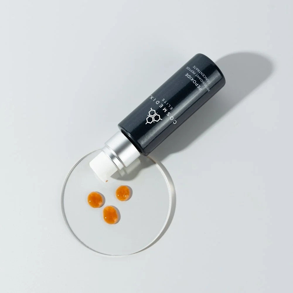Pepoxide Antioxidant Peptide Concentrate product bottle laying down on petri dish with orange colored product swatches