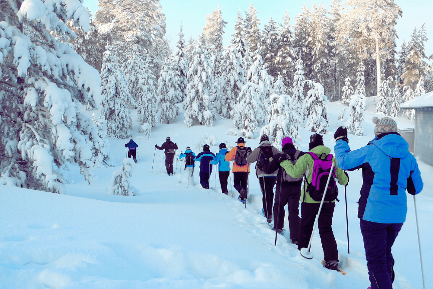 People snowshoeing in single file on a snowy trail