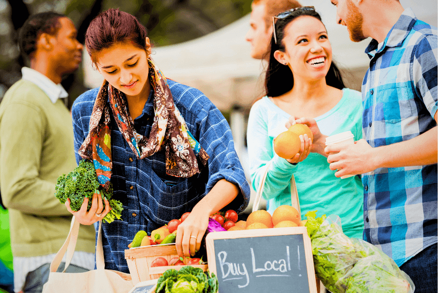 People shopping at a farmer's market using reusable bags