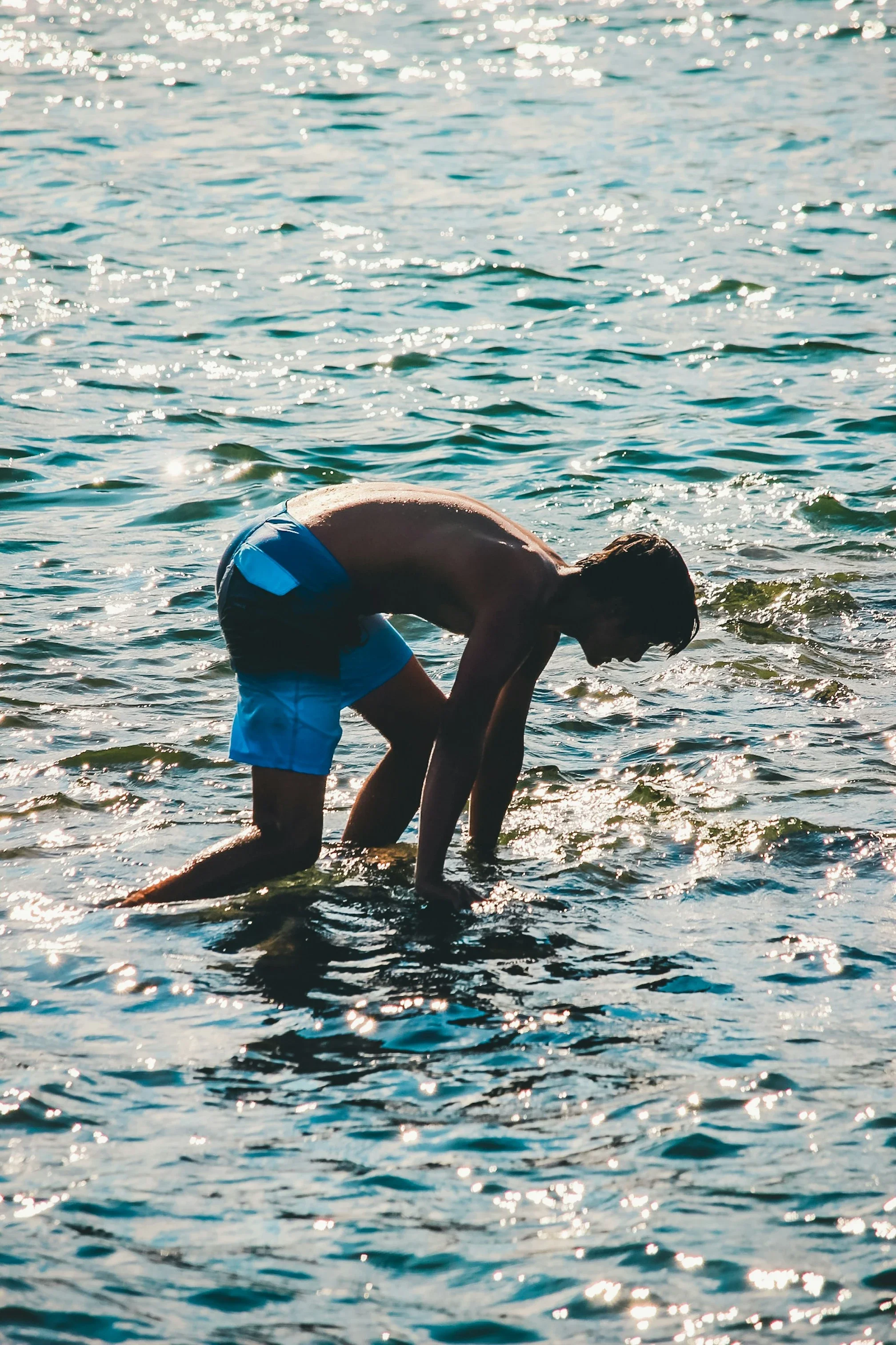 photo of a man walking through shallow water in bright sunshine
