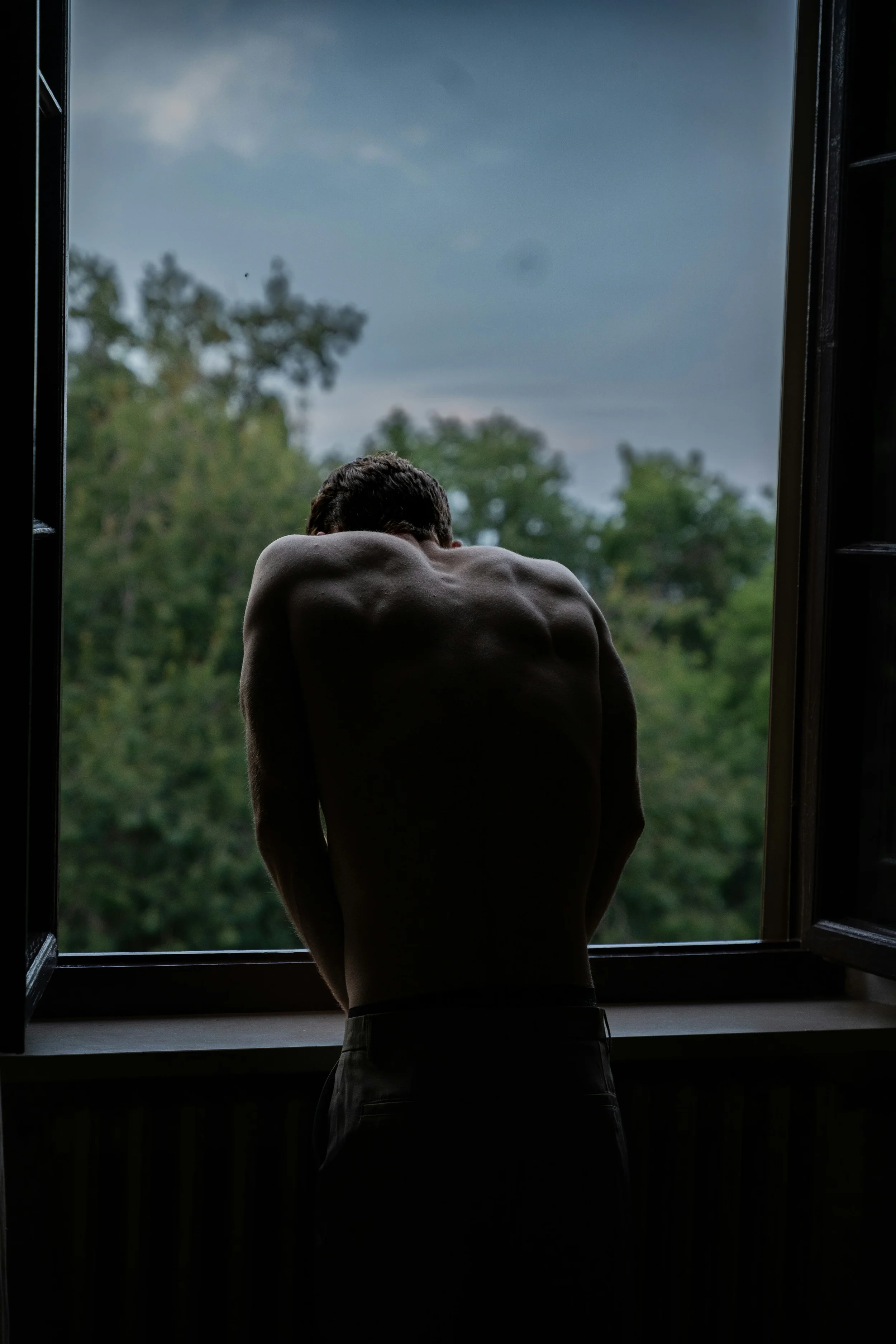 photo of a muscular man leaning out a window