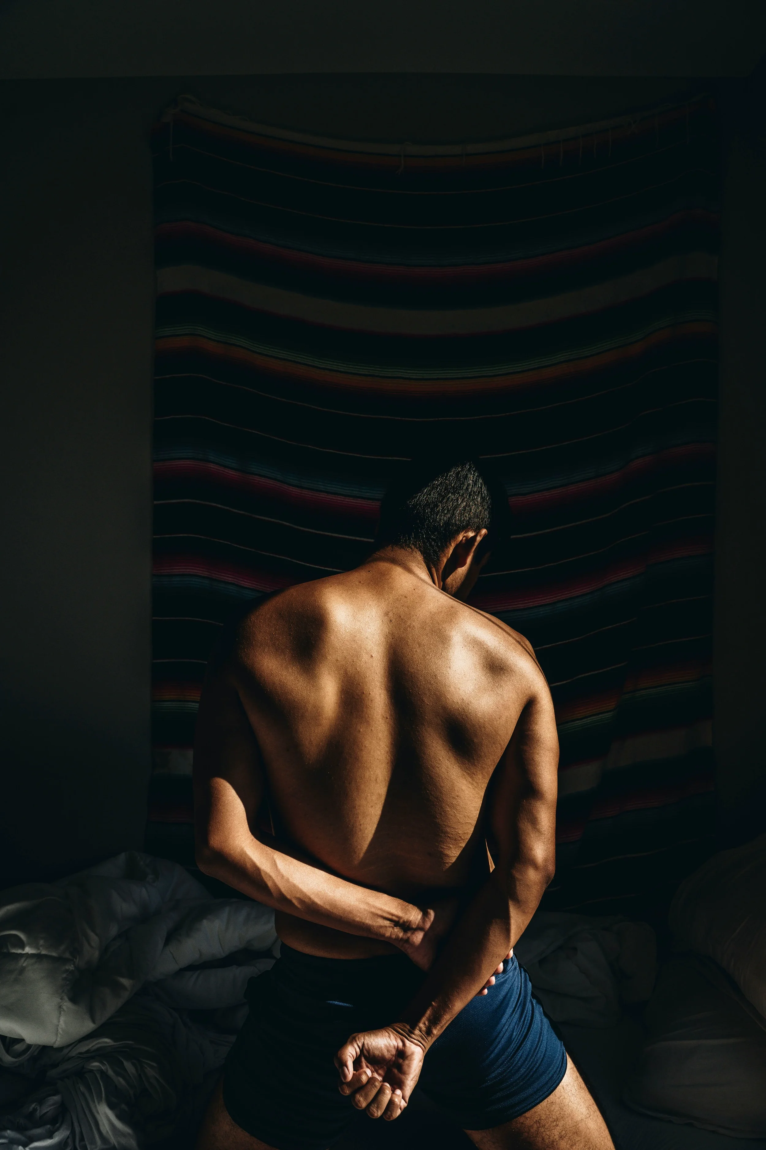 photo of a man from behind in a shadowy room butt wax