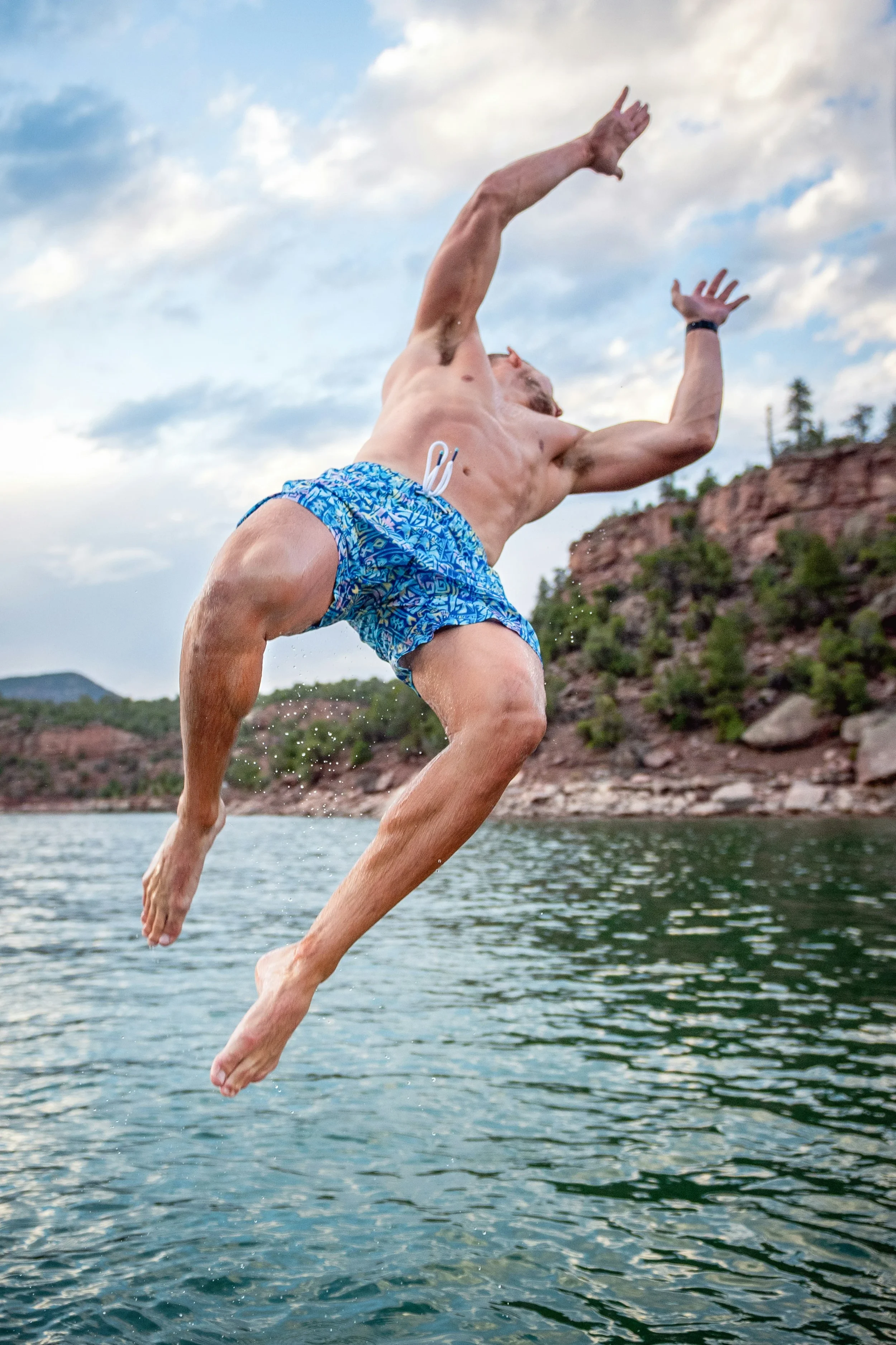 photo of a man in a bathing suit leaping off a cliff into the water below
