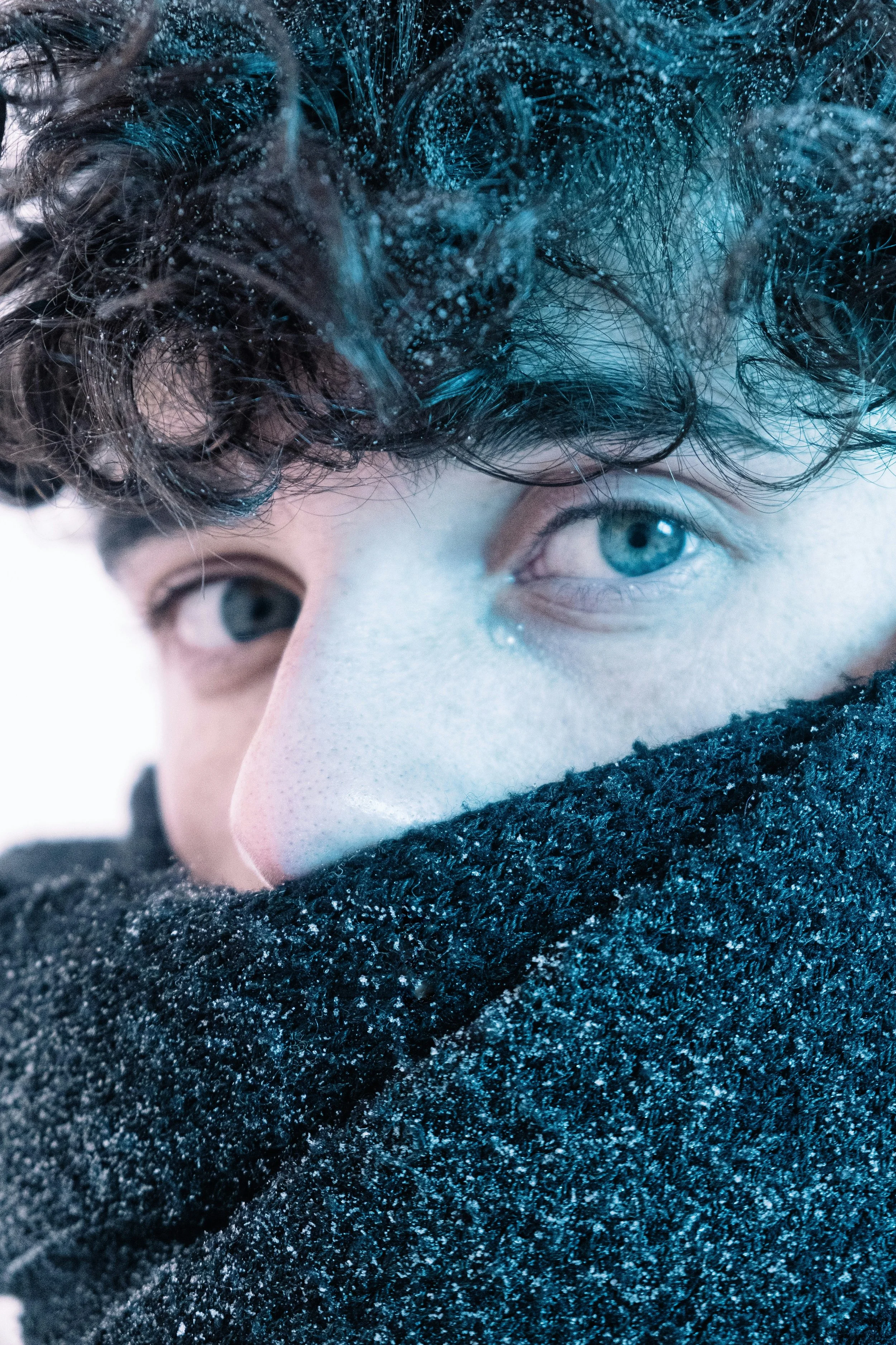 Silhouette of a shirtless person with short hair and a necklace, facing to the left, with shadows cast on a wall behind him.