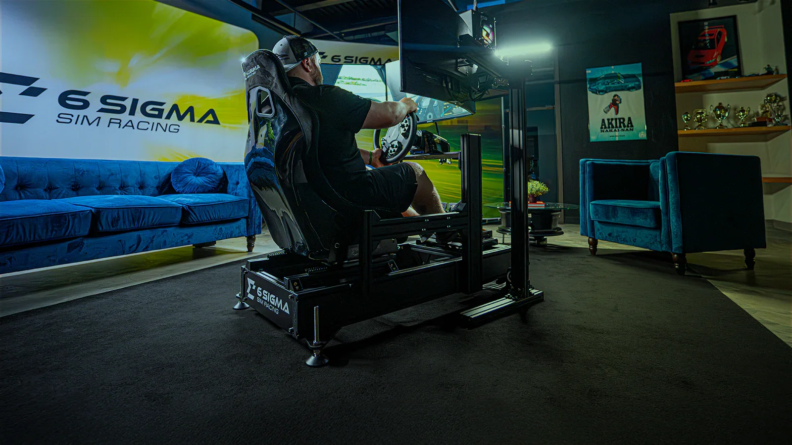 Person using a racing simulator setup in a room decorated with racing posters and trophies, sitting in a gaming chair in front of multiple monitors.
