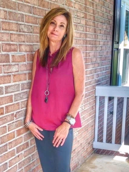 Smiling woman leaning up against a brick wall