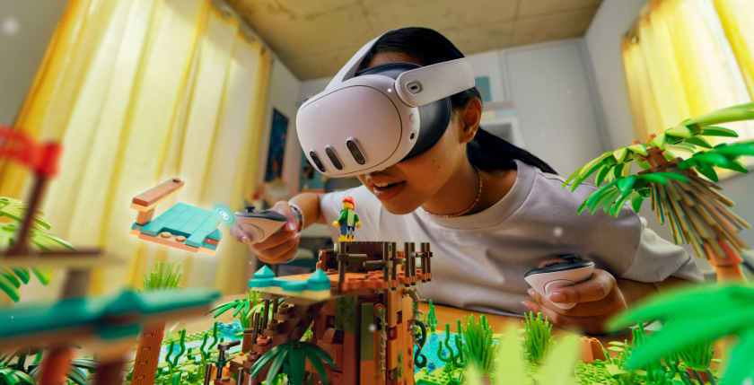 Woman using a VR Oculus Quest 3 headset and controllers to interact with a colorful LEGO digital landscape featuring trees, plants, and a small LEGO figure.